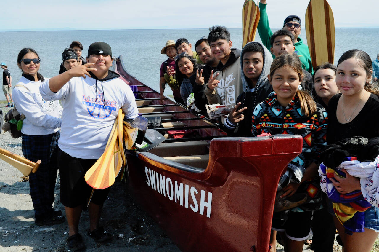 Sequim Gazette photo by Jacques Star/ Chas James, left, holding paddles, and Danielle James (right, in traditional dress), along with their Swinomish Tribe canoe mates, gather their paddles after reaching the shore at Jamestown Beach, where they were greeted by members of the Jamestown SKlallam Tribe and others after completing another leg of the annual Canoe Journey. The Paddle to Elwha was hosted by the Lower Elwha Klallam Tribe. The protocol and celebration took place Aug. 1-5.