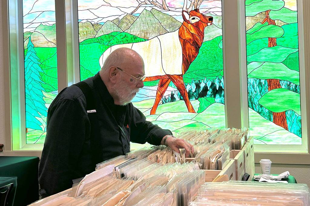 Sequim Gazette photo by Matthew Nash/ Collyer Church of Bainbridge Island looks through a dealers stamps at the Strait Stamp Show in Sequim on Aug. 9. He tries to visit the Sequim show each year and said Its a good little show. The people are friendly and the exhibits are fascinating and they show what people really collect, he said.