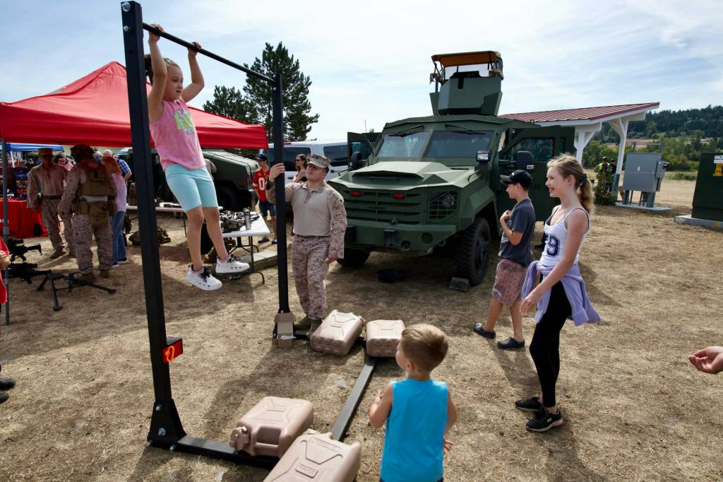 Kanya Weinert attempts pull-ups, U.S. Marine Corps style, under the encouragement of Staff Sgt. Roscoe, her brother Zayden Weinert (dark shirt and cap) and friends Olivia Blank, right, and Enzo Blank.