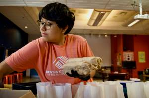 Arrow Edgecomb fills lunch sacks with Italian subs.