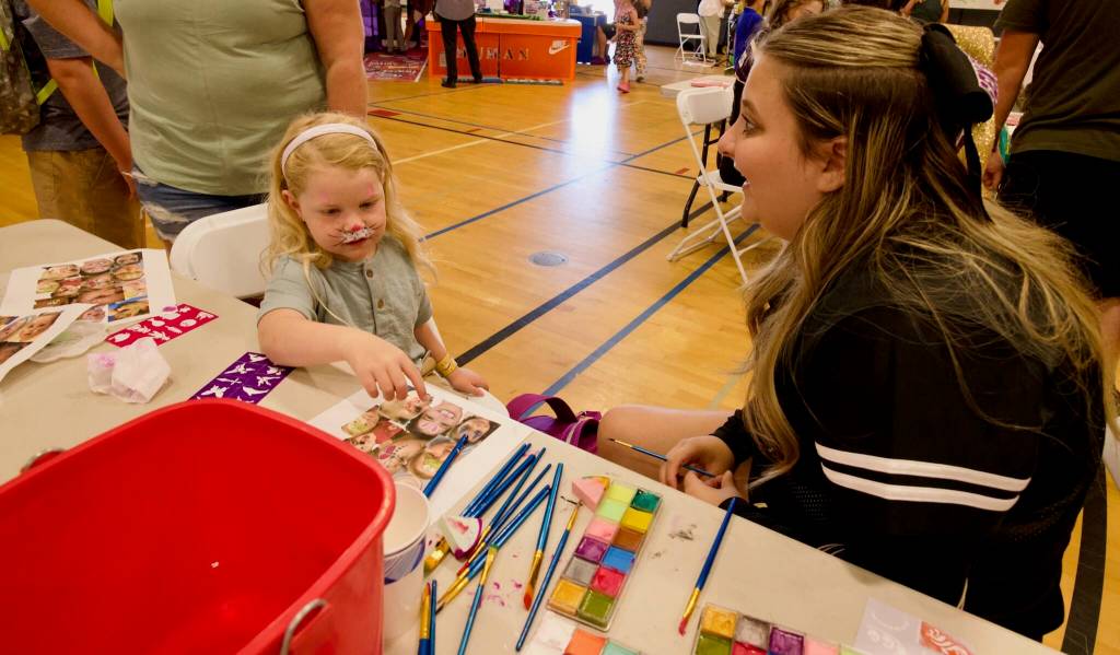Sequim High School Cheerleader Riley Campbell (left) helps Addy Galloway (left) pick out a face paint character.