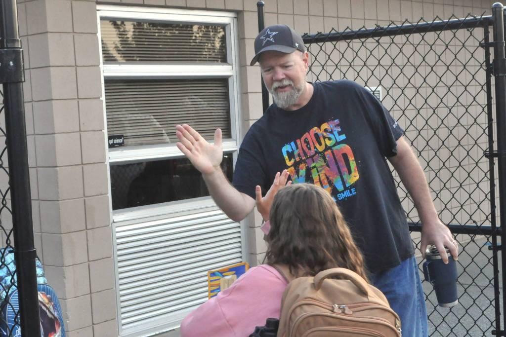 Sequim Gazette photo by Matthew Nash/ Jay Earley, a living skills paraeducator, gives high fives to students as they walk onto Helen Haller Elementary Schools campus on Aug. 27, the first day of school.