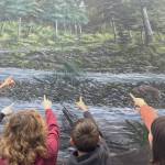 Sequim Gazette photo by Matthew Nash/ Students do a search for various animals, including an elk, on a Tim Quinn mural on the side of the Dungeness River Nature Center with help from Olympic Peninsula Audubon Society volunteer Bob Boekelheide.