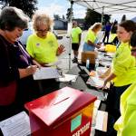 Sequim Gazette photo by Jacques Star
Joan Plumb, second from left, instructs fellow volunteer Lori Grouper, left, on how to sign in at Sequim Food Banks inaugural Everyone at the Table dinner/fundraiser, held Saturday at the food bank, located at 144 W. Alder St. Twenty volunteers pitched in to man outdoor tables, where attendees could sample food, obtain recipes and learn about the food banks services. Sequim Food Bank has seen a dramatic increase this year in those needing food assistance.