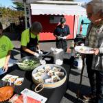 Sequim Gazette photo by Jacques Star/
John Flower stops by a booth at Sequim Food Banks Everyone at the Table fundraiser where Nicole Hartman of Sequim Sunrise Rotary prepares Romesco sauce to serve with crabless cakes.