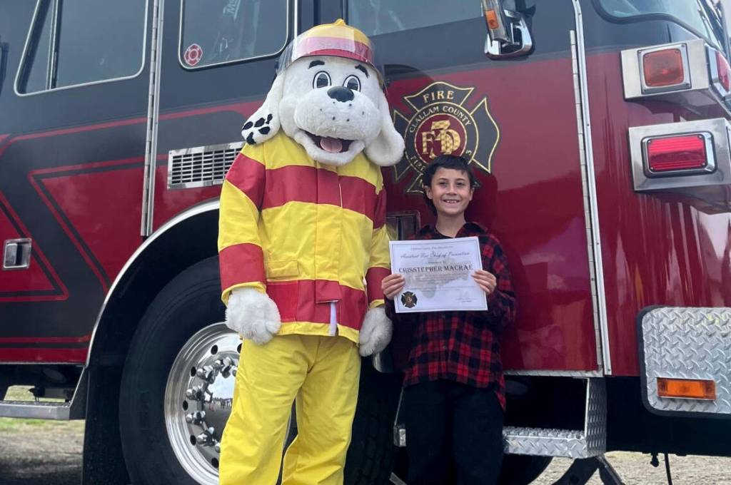 Photo courtesy Hayley Jennings
Sparky the Fire Dog was able to connect with Crisstepher MacRae at the Clallam County Safety Fair on Saturday, where the mascot presented the youngster with a certificate proclaiming him honorary assistant fire chief for prevention during Fire Prevention Week. Crisstepher won the title  and a trip to or from school on a fire truck  for his Fire Escape Plan diagram of his familys home.