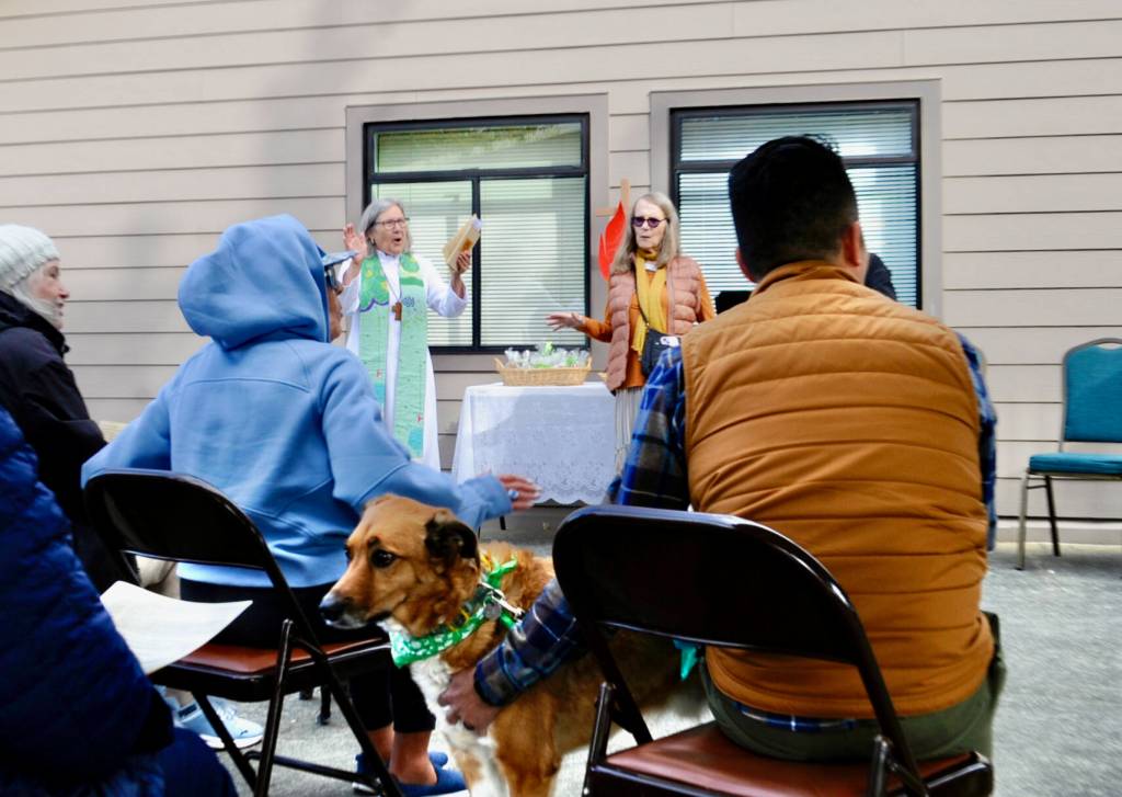 Rev. Dr. Desi Larson (middle, left) sings with Gwen MacRae (middle right) along with David Ham (right) and Rev. Larsons dog Buster, a Heeler/Cattledog (middle) sing a hymn written by St. Francis called All Gods Creatures. St. Frances was believed to have an uncanny ability to communicate with animals, and his deep understanding of our relationship to them is celebrated in the Blessing of the Animals.
