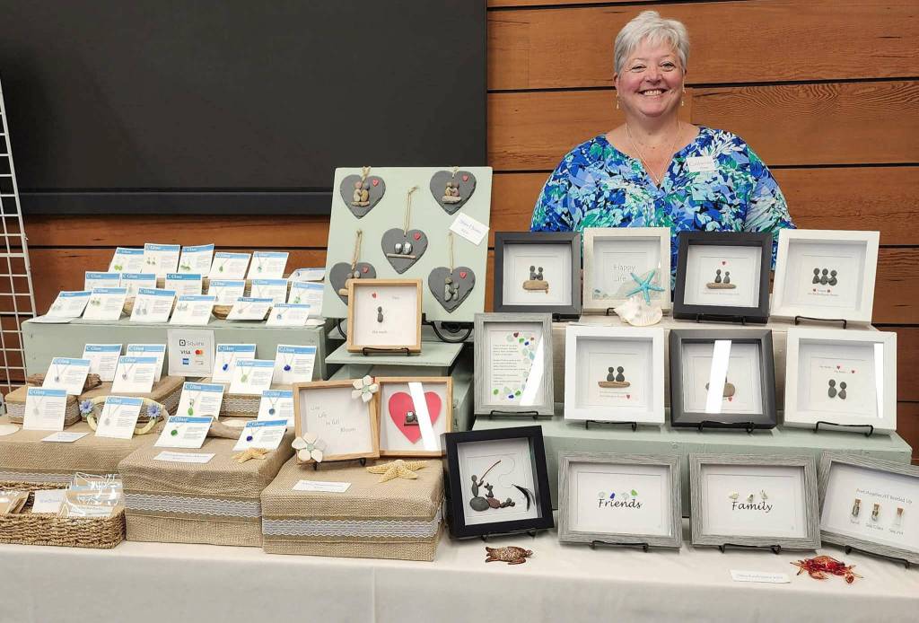 Photo courtesy Catherine Lanham/ Catherine Lanham poses with some of the sea glass jewelry and shadow box art that she sells at her C Glass table at the Shipley Center Holiday Bazaar.