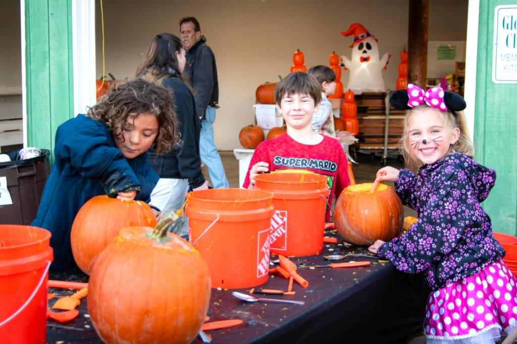 Photo by Monica Berkseth/
Children carve pumpkins on Oct. 25 at the Sequim Prairie Granges Country Fair and Trunk-or-Treat.