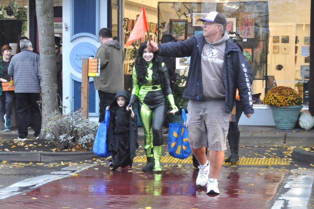 Sequim Gazette photo by Matthew Nash/
Volunteer Stephen Rosales leads families across a Washington Street crosswalk on Halloween. He was one of many volunteers through the Sequim-Dungeness Valley Chamber of Commerce to help people safely cross the street.