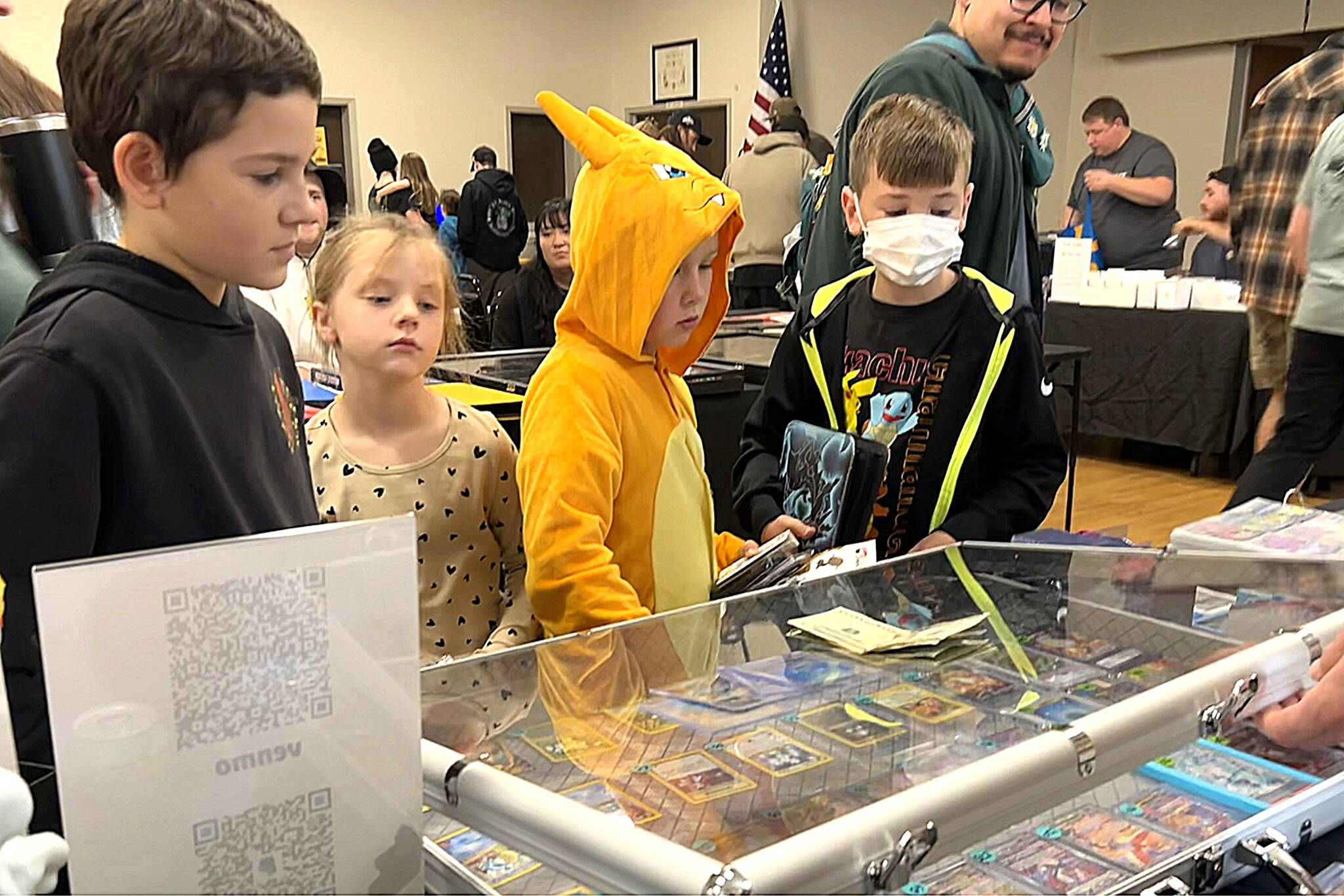 Hayden Martinez, McKenna Perry, Connor Perry, and Henrik Lowrey look to buy some Pokémon cards from a vendor at the Card and Pokémon Show inside the Sequim Elks Lodge on Nov. 8.