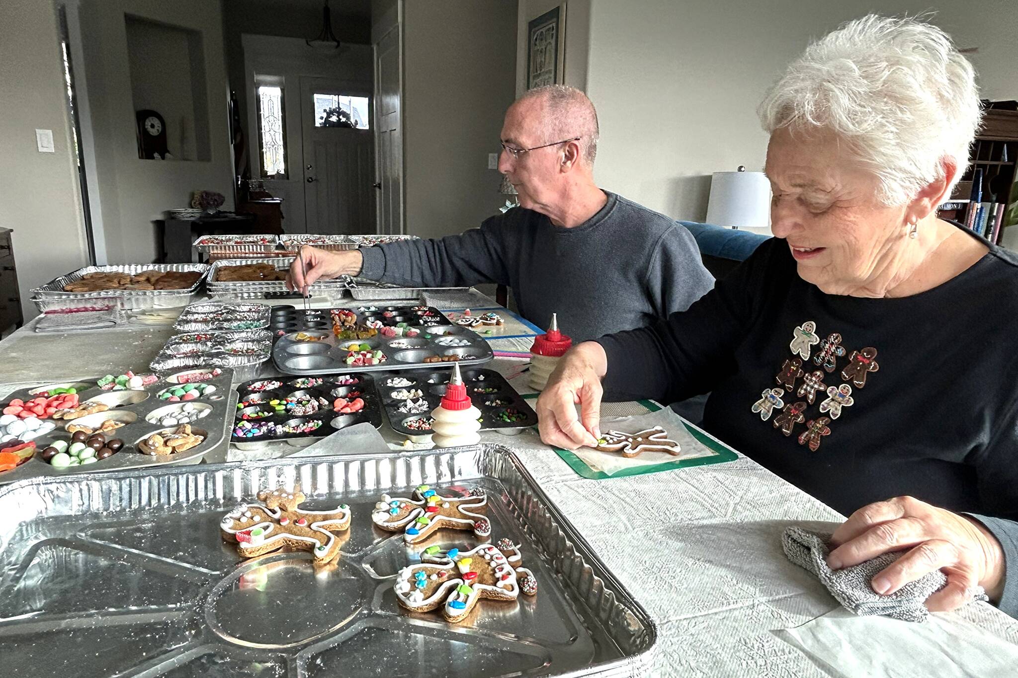 Sequim Gazette photos by Matthew Nash
Doug Woodall helps his neighbor Vera Felts decorate one of many gingerbread cookies for the Sequim Guild of Seattle Childrens Hospitals Holiday Bazaar on Nov. 22 in the Sequim Prairie Grange. This year, she estimates 20 neighbors have helped her decorate cookies to help local children with uncompensated care.
