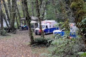 Forks medics await at the scene on the Bogachiel River near the Goodman Mainline west of Forks on Thursday afternoon after a boat overturned. Forks medics, law enforcement, Clallam County Fire District 1 and airlift all responded. Two people died and a third person is still missing, the Clallam County Sheriffs Office said. (Lonnie Archibald/for Peninsula Daily News)