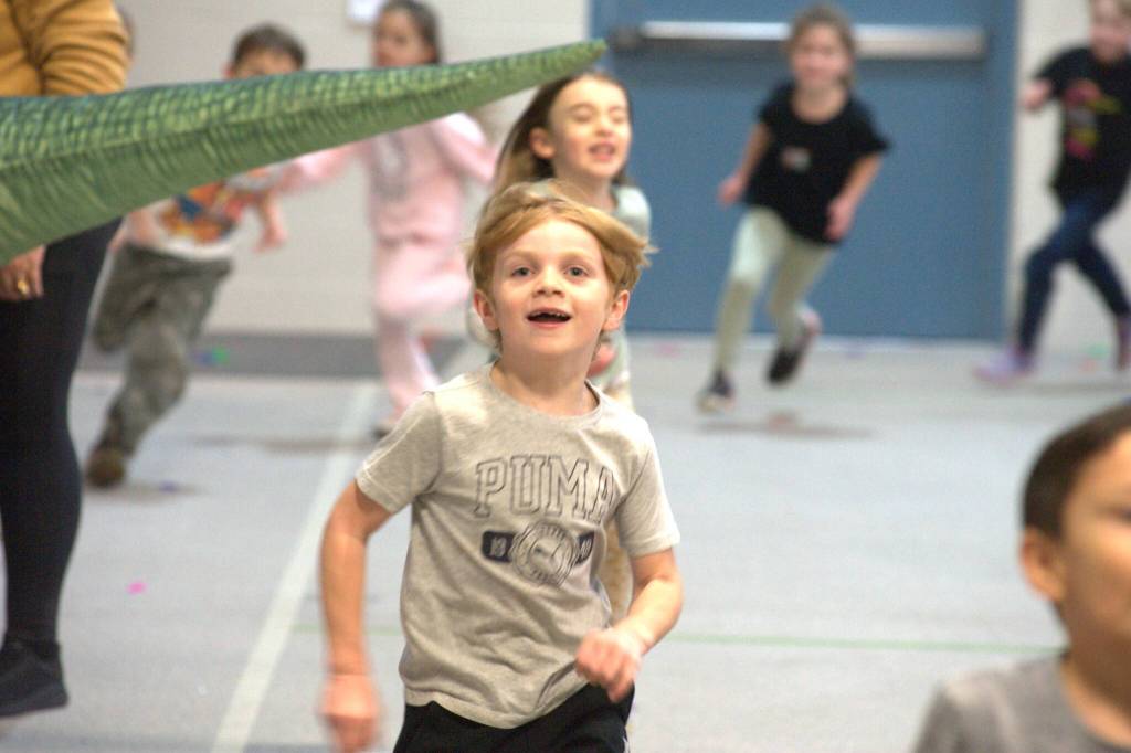 Sequim Gazette photo by Matthew Nash/
First grader Kade Eastburn smiles after passing underneath a dinosaur tail during Greywolf Elementarys Turkey Trot.