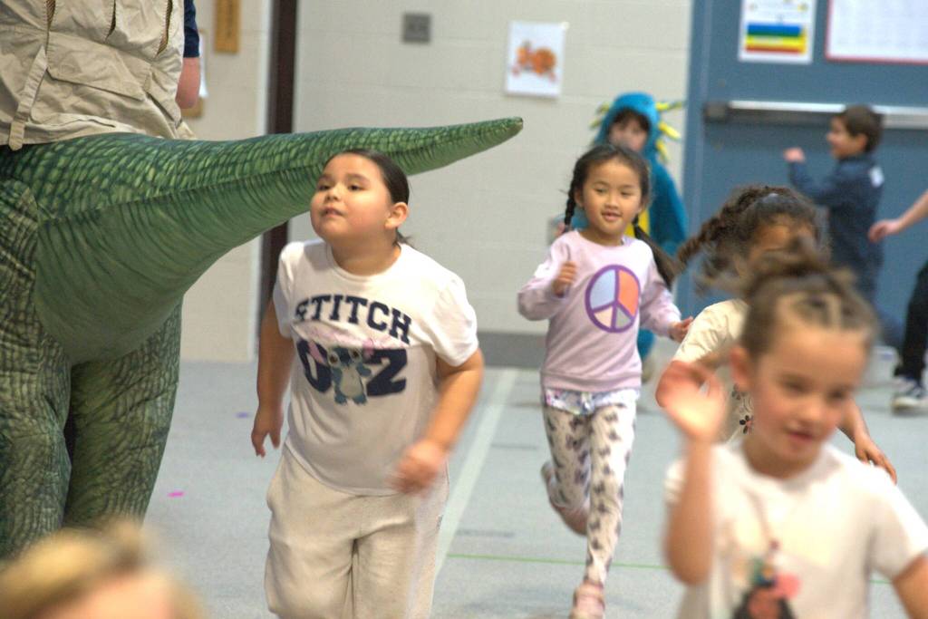 Sequim Gazette photo by Matthew Nash/
Diana Bahena Torres continues her lap during the Turkey Trot at Greywolf Elementary while doing the limbo under a dinosaur tail.