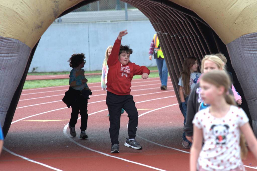 Sequim Gazette photo by Matthew Nash/
Jason Hadley does a skip jump through the inflatable Sequim Wolf during the Turkey Trot with fellow Helen Haller Elementary students.
