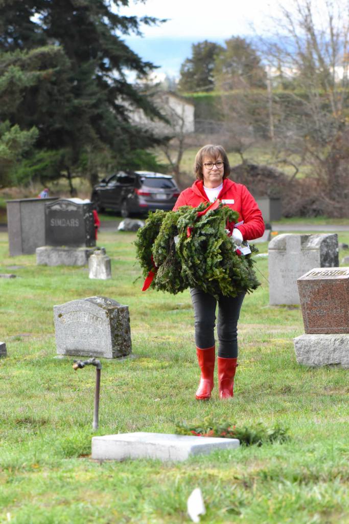 Sequim Gazette photo by Monica Berkseth/ Anita Reynolds, New Dungeness Chapter DAR regent, carries wreaths for placement on veterans graves at Sequim View Cemetery on Saturday, Dec. 13 as part of the Wreaths Across America national initiative.