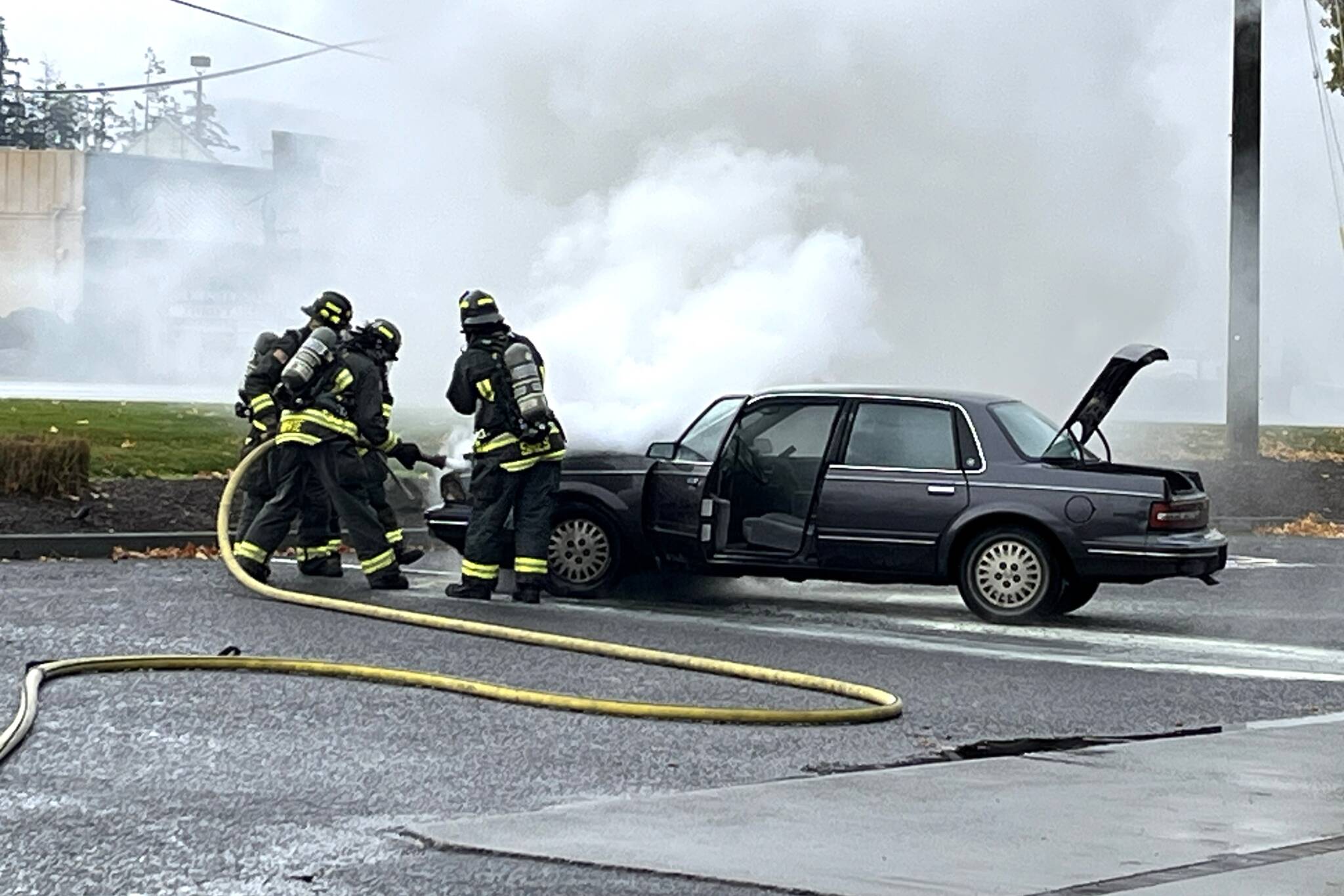 Photo courtesy Chris Turner, CCFD3 
Clallam County Fire District 3 firefighters spray water inside a car hood on Dec. 10 to extinguish flames near the Sequim Safeway fuel station.