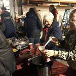 Sequim Gazette photo by Matthew Nash
Karen Eldridge, on right, pours a warm apple cinnamon drink for Brian Hanley as Barb Parse prepares another drink during a Sunland block party on Dec. 11. Neighbors offer cookies, warm drinks and a campfire each year as they await Santas Toy and Food Fire Brigade.