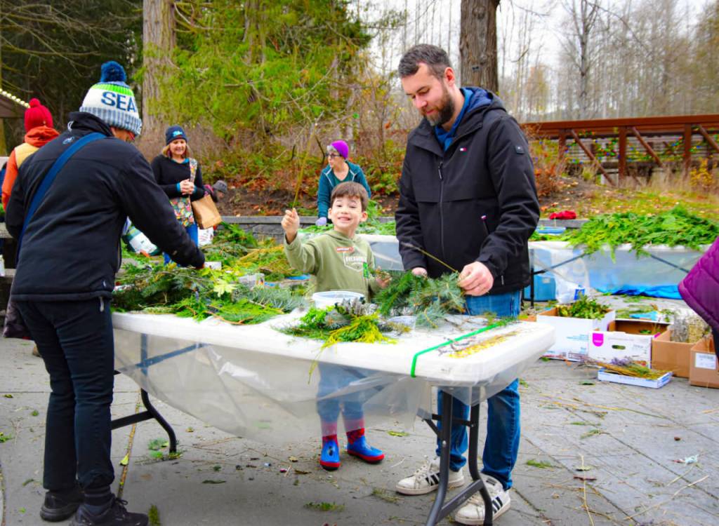 Sequim Gazette photo by Monica Berkseth/ Jon Alderson and his five-year-old son, Kadin, make wreath-making a father-son project during the Dungeness River Nature Centers annual Holiday Nature Mart.