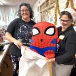 Morgan Mortensen, left, and Bonita Jarvis work together to put a giant Spider Man plushy into a bag for a present on Christmas morning.