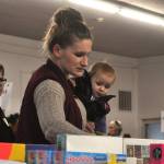Sequim Gazette photo by Matthew Nash/
Shauna McNally with 14-month-old Baileigh looks for board games for her family as volunteer elf Bonita Jarvis, on left, helps hold her items.