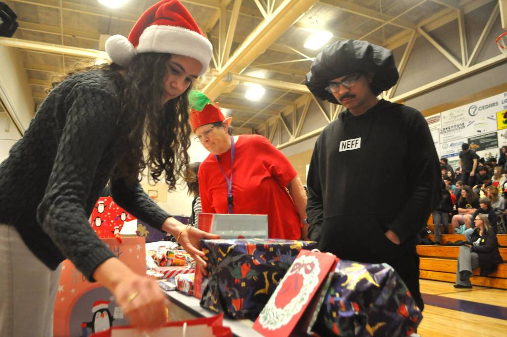 Laila Sundin helps look for a present for Jaron Aiken during the SHS Winter Wishes assembly.