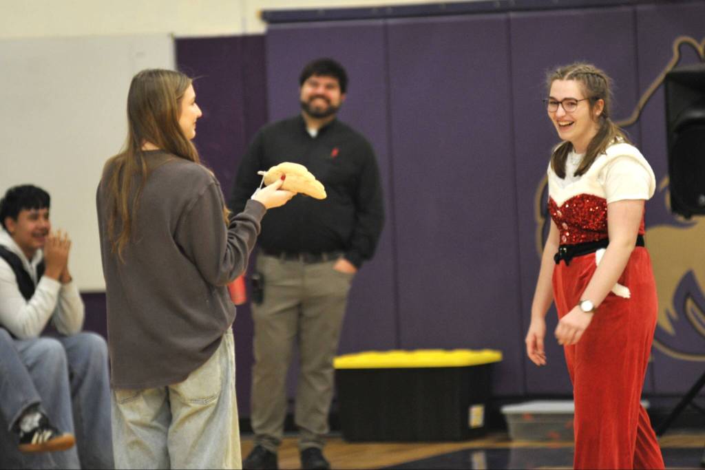 Senior Emma Gilliam, right, surprises her sister, Leah, a sophomore, on left, with a croissant Jellycat plushy during the Winter Wishes assembly.