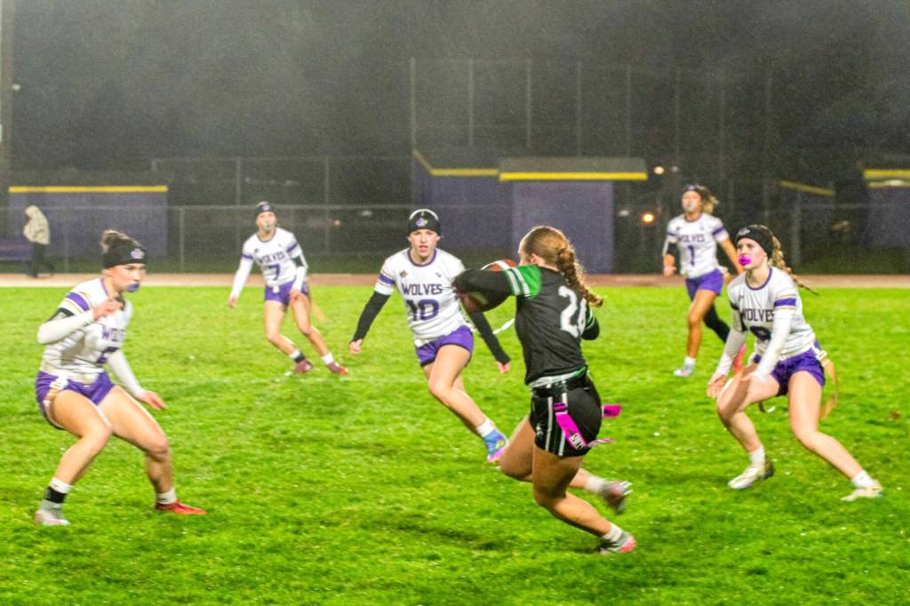 Sequim players surround a Port Angeles player on Dec. 18 during a windy and rainy game.
