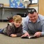 Sequim Gazette photo by Monica Berkseth/ Eric Pickens and kindergartener Carter Tyler enjoy some one-on-one storytime.