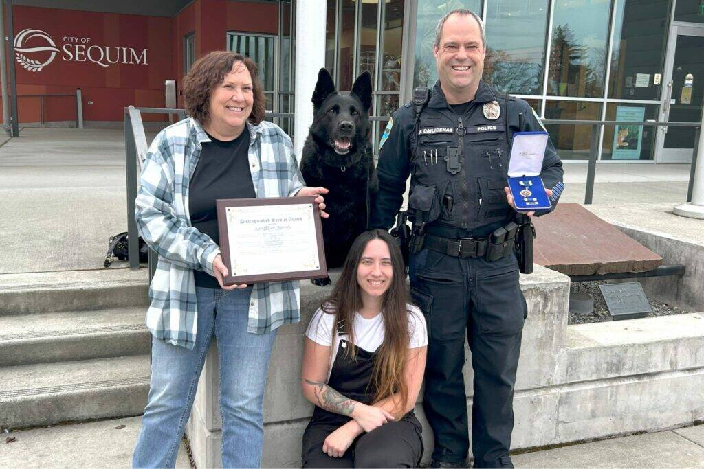 Sequim Gazette photo by Matthew Nash
Mamba the dog sits at the Sequim Civic Center with her family – Sequim Police Officer Paul Dailidenas, his wife Linda, left, and their daughter Alyssa on March 10 after Dailidenas and Mamba received a Distinguished Medal. Mamba retired from service after nearly eight years, and Sequim is training another officer and dog to take over the K-9 Officer Program with Dailidenas blessing.