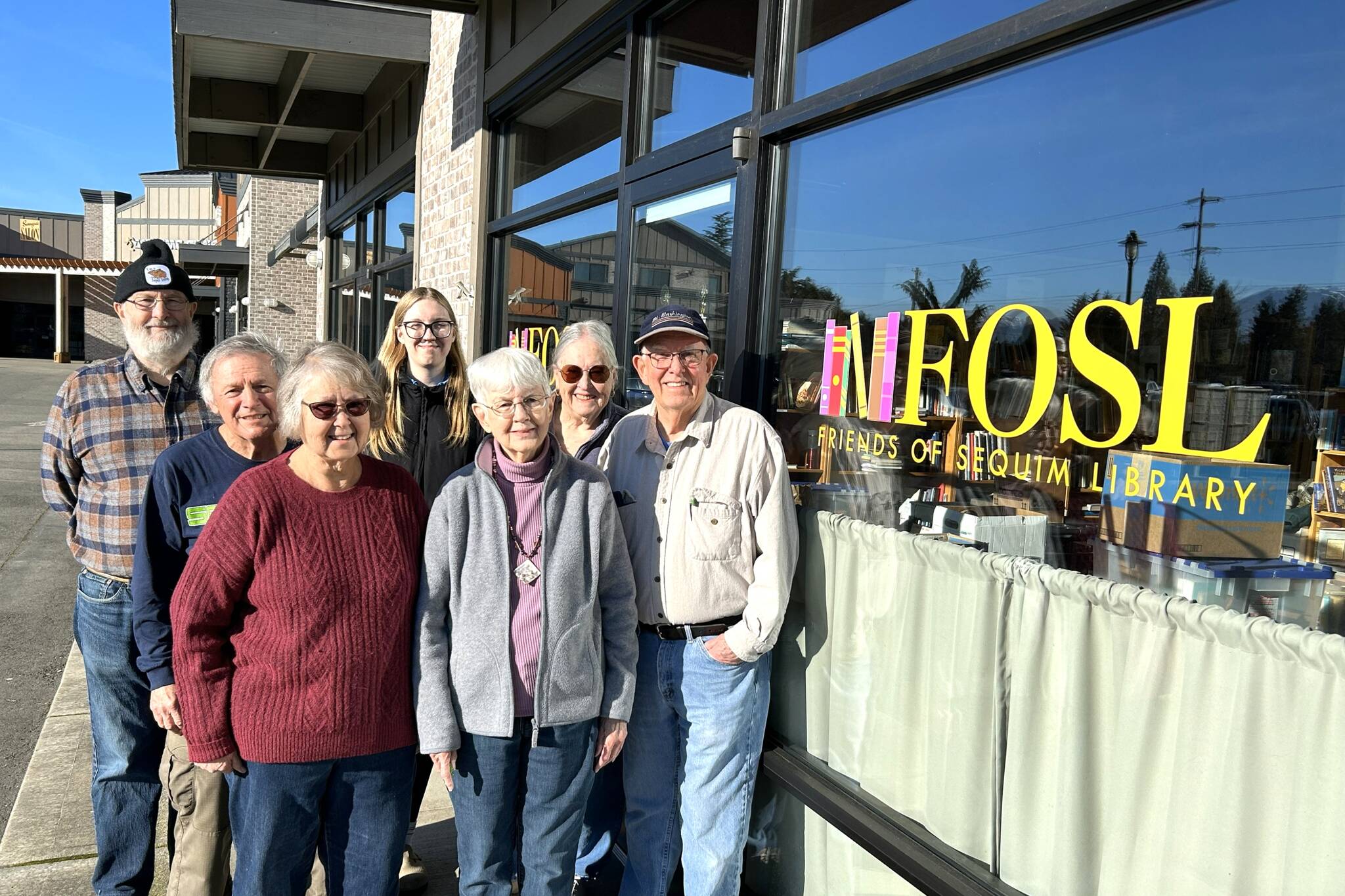 Sequim Gazette photo by Matthew Nash
A few of the Friends of Sequim Library, from left, Bob Pasco, Rick Yates, Linda DeMoss, Siobhan Robinson, Pam Carter, Barbara Erler, and Roger Uhden stand outside the storefront in Rock Plaza at 10175 Old Olympic Highway in Sequim. Donations are accepted 10 a.m.-1 p.m. Mondays and Wednesdays, except for the Wednesday before their monthly sales on the second Saturday of each month.
