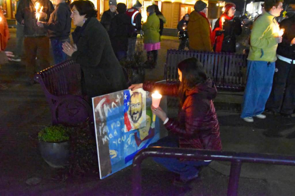 Sequim Gazette photo by Monica Berkseth/ A woman examines a painted sign depicting deceased Minneapolis residents Alex Pretti and Renee Good while Congresswoman Emily Randall, left, speaks with a constituent.