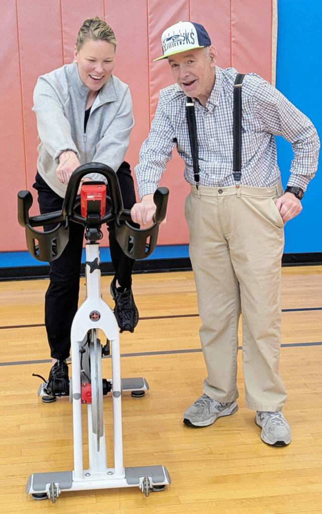 Photo courtesy Olympic Peninsula YMCA/ Instructor Christine Senter, left, reviews parts of a spin bike with a Y member in preparation for a Pedaling for Parkinsons class.