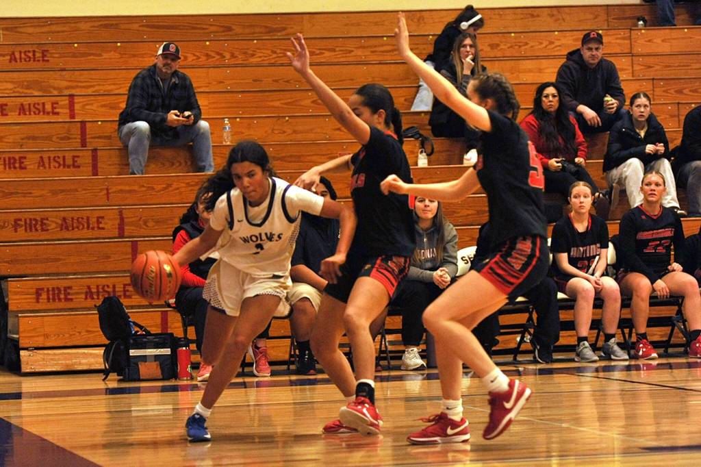 Sequim Gazette photo by Matthew Nash/ Jordyn Julmist drives the baseline against two Orting defenders.