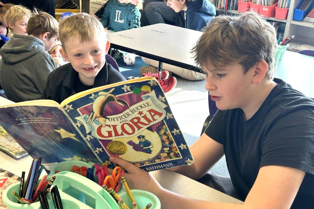 Silas Sullivan, a Sequim eighth grader, reads to Greywolf kindergartener Travis Hvass a copy of Officer Buckle and Gloria.