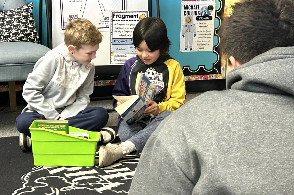 Sequim Gazette photo by Matthew Nash/
Helen Haller Elementary third graders Mason Wright and Ollie Mounts read a copy of Big Nate with a Sequim high schooler on March 2.