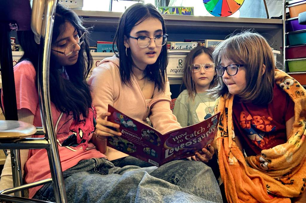 Sequim Gazette photo by Matthew Nash
Sequim Middle School eighth graders Sophia Salgado and Taylor Matlock read How to Catch a Loveosaurus with Greywolf Elementary second graders Lara Fraser and Juliuet Rojers-Young on Monday for Sequim School Districts celebration of Read Across America.