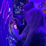 Sequim Gazette photo by Matthew Nash/ Sisters Clara and Paige Cerfogli of Sequim enjoy the Glow Zone at the Sequim Sunshine Festival where they drew pictures on paper with bright markers underneath black lights.