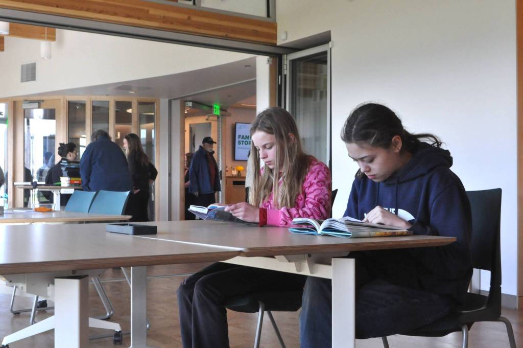 Sequim Gazette photo by Matthew Nash/ Ruth Scheet and Violet Bays read graphic novels together at a table together inside the renovated Sequim Library on reopening day.