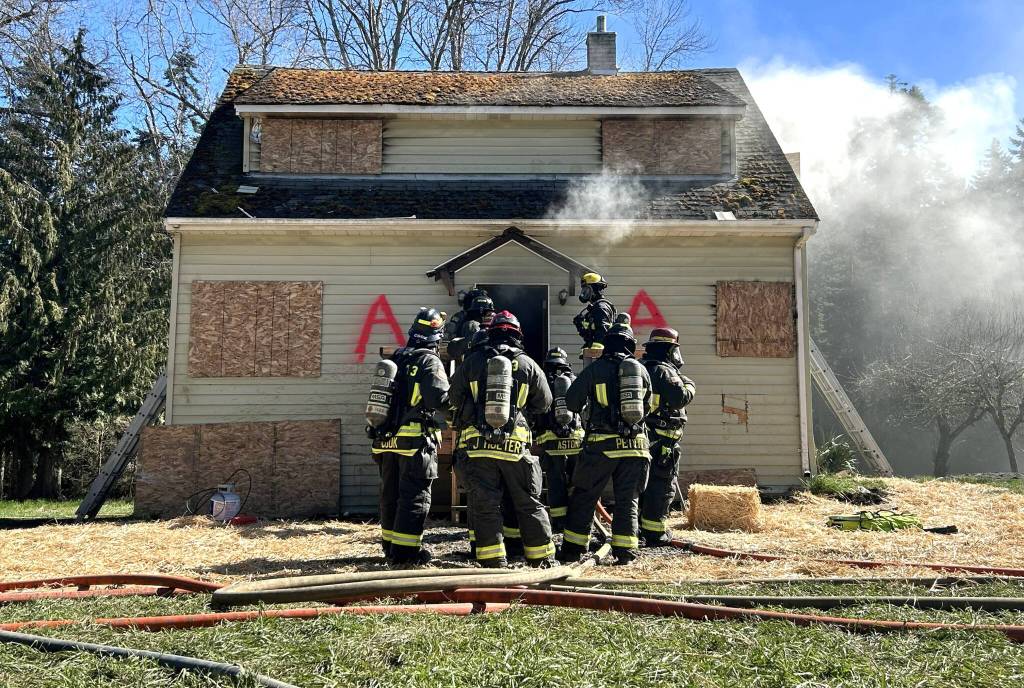 Sequim Gazette photo by Matthew Nash/ A group of Clallam County Fire District 3 firefighters prepare themselves before going inside the ground floor of a live-fire training on March 21.