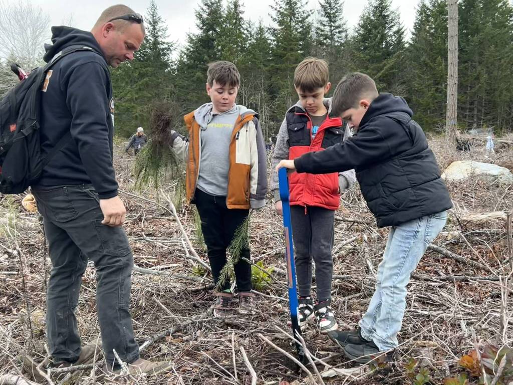 Sequim Gazette photo by Matthew Nash/
Volunteer Jason Lewis works with Emett Horness, Adrian Herrera and Jackson Lewis to find great spots to plant trees off Blue Mountain Road.