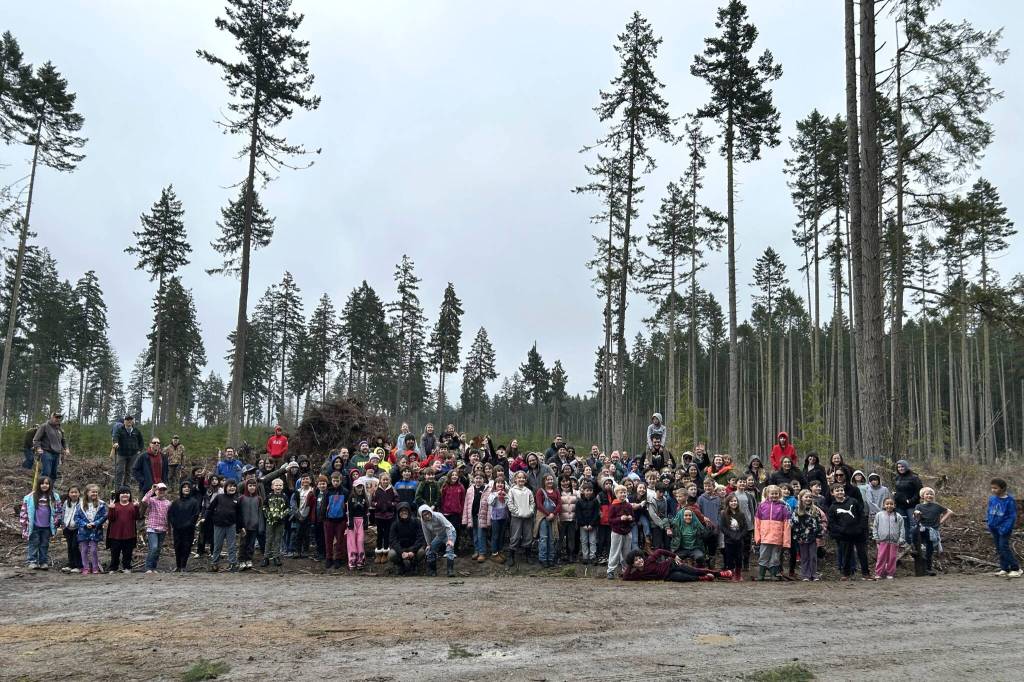 Sequim Gazette photo by Matthew Nash/ Third grade students, parents and volunteers from Helen Haller Elementary stand with various forestry volunteers on March 25 after planting hundreds of trees on state trust lands off Blue Mountain Road.
