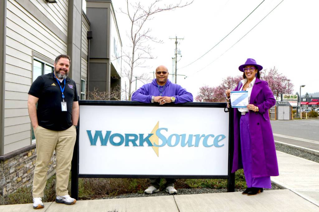 Photo by Monica Berkseth
Alicia Liggins, right, holds the award that she and her husband Darrin Liggins, center, received from David Herrick, left, of WorkSource Clallam County. The couple own Liggins Landscaping in Sequim and are the founders of the nonprofit Having Understanding Means Acting Now (H.U.M.A.N.), which provides workforce assistance to individuals.