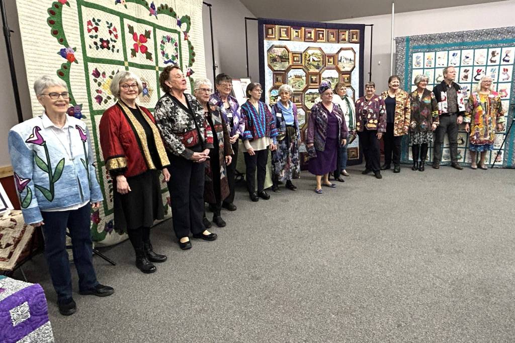 Models for the Wearable Fashion Show during the Sunbonnet Sue Quilt Clubs 40th anniversary stand for a photo in the Sequim Masonic Lodge after they walked through the crowd showing off their outfits.