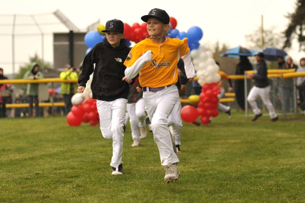 Sequim Gazette photo by Matthew Nash/
Players with Rainshadow Coffee Roasters majors baseball team run out during the Player Parade on April 11 for opening day of Sequim Little Leagues season.