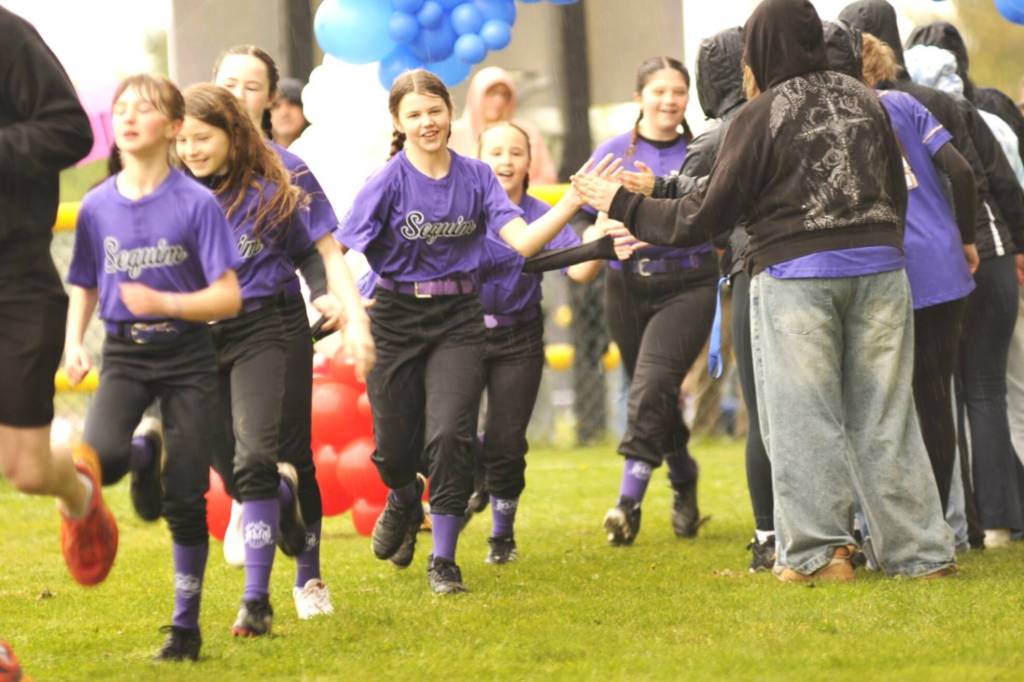 Abby Daly, 12, in center, runs onto the field with teammates of her minors softball team on April 11. She received the game ball from her coach for pitching in their win.