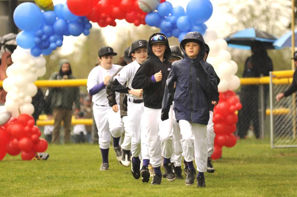 Sequim Gazette photo by Matthew Nash/ Colin Hiday Concretes majors baseball team runs onto the field during the Player Parade.