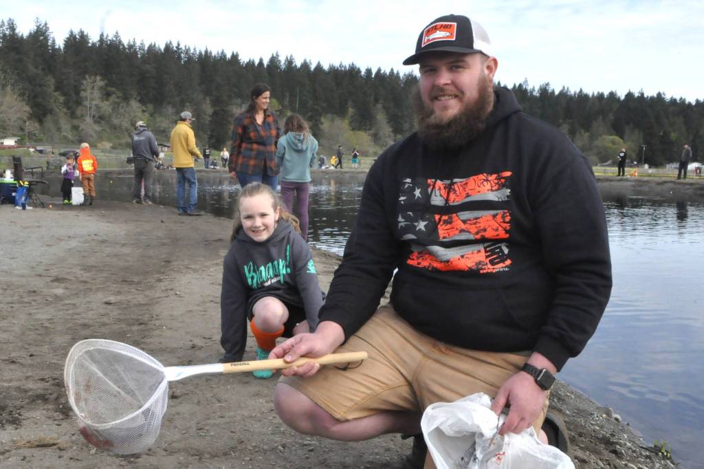 Colby Martin holds the fish his stepdaughter Jordyn Staus, 7, caught during Kids Fishing Day at the Water Reuse Pond. She caught two fish last summer and this was her first in Sequim.