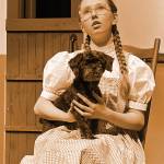 Sequim Gazette photo by Matthew Nash/
Sequim freshman Trinity Devlin as Dorothy sits in front of her Kansas house with Toto (Arrow the dog) during a scene from SHS Operetta Clubs The Wizard of Oz. Devlin said she prefers doing the show with a real dog. Its been really fun, she said.